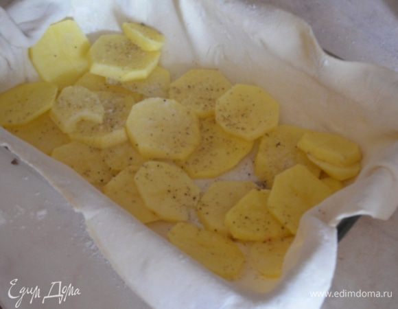 Дно прямоугольной формы для запекания смазать маслом, выложить в нее кусок теста побольше, а на него раскладываем 1/2 картофеля нарезанный а тоненькие кружочки. 