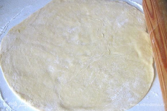 Разделить тесто на 2 неравные части, большую раскатать на рабочей поверхности, присыпанной мукой, в круг, чтобы тесто было размером чуть больше, чем дно разъемной формы, чтобы его хватило на небольшие бортики.
