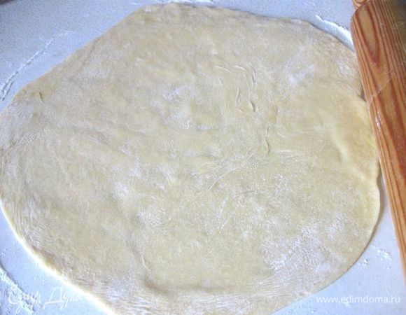 Разделить тесто  на 2 неравные части, большую  раскатать на рабочей поверхности, присыпанной мукой, в круг, чтобы тесто было размером чуть больше, чем дно разъемной формы, чтобы его хватило на небольшие бортики.