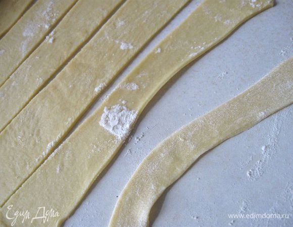 На нее – измельченную  зелень. Оставшееся тесто раскатать тоньше предыдущего пласта. Нарезать на полоски, которые произвольно положить сверху начинки, слегка помазав с одной стороны молоком с помощью кисточки.