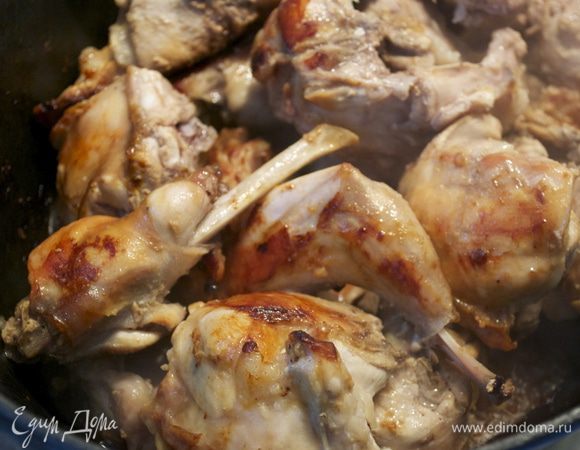 В большой кастрюле с тяжелым дном растопить масло, выложить кролика и обжарить со всех сторон до золотистой корочки.