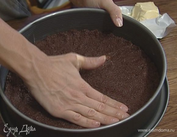 Разъемную форму для выпечки смазать сливочным маслом, выложить тонким слоем печенье с маслом и поставить в разогретую духовку на 10 минут.