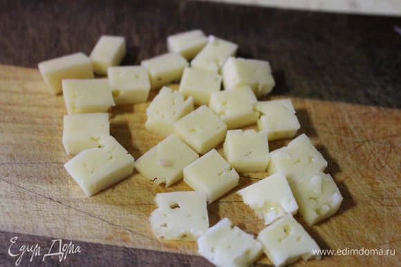 Один ломтик сыра нарезать на полоски, а потом на кубики.
