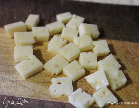 Один ломтик сыра нарезать на полоски, а потом на кубики.