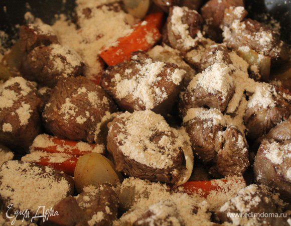 Посыпать мукой, хорошо перемешать и слегка обжарить. Добавить раздавленный чеснок.