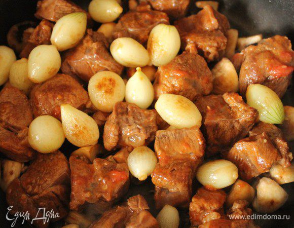 Переложить на грибы мясо, сверху положить луковички.