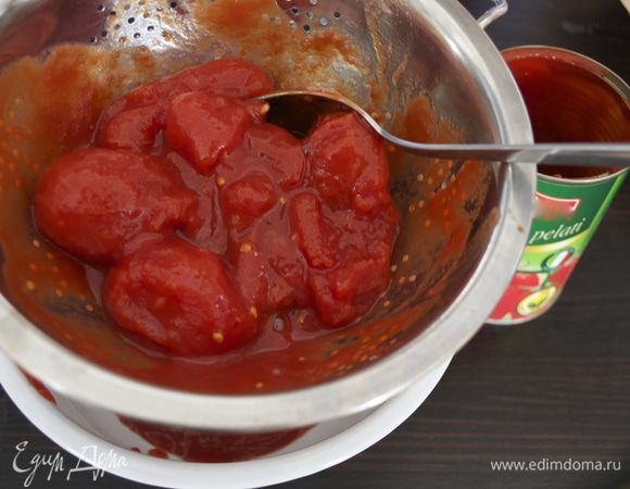 Тем временем, духовку включить разогреваться на 200 С. Помидоры в собственном соку выложить из банки в дуршлаг и дать стечь лишней жидкости (соку). ВАЖНО, постараться удалить как можно больше лишней жидкости, чтобы тесто пиццы не намокло. (Сок, естественно, не выбрасывать..., использовать для соусов, приготовления других блюд).