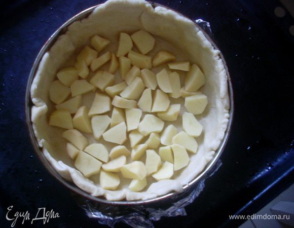 Отделить от теста 2/3 объема и раскатать круглую лепешку. Сложить лепешку в форму или сковороду для запекания, так, чтобы тесто доходило до краев бортиков. Разложить на дно половину объема картофеля. 