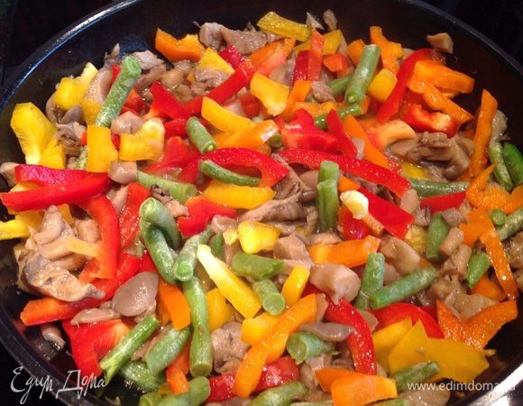 Добавьте к грибам 1 ст л оливкового масла, перец, фасоль (не размораживая, если она была заморожена), выдавленный прессом чеснок. Накройте крышкой и тушите на среднем огне около 4 минут.