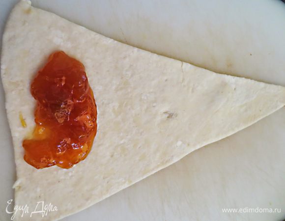 Готовое тесто разрезать на треугольники. С широкой стороны выложить начинку