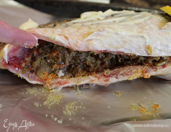 Рыбку помыть, обсушить, внутри и снаружи посыпать приправой для рыбы, обмазать сметанкой. В места, где были жабры положить по кружочку лимона. Брюшко нафаршировать капустно-икорной начинкой.