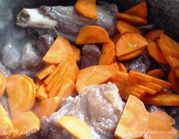 Когда мясо подрумянится,  добавить морковь и, помешивая, обжарить до золотистого цвета. 
