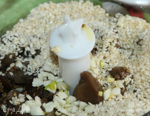 Баклажаны, 5 столовых ложек кунжута, 1 зубчик чеснока (мелко нарезанный) и 3 столовые ложки оливкового масла отправляем в чашу блендера.