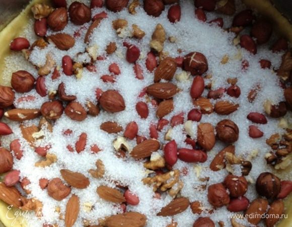 Из одной раскатать корж, выложить его в разъемную форму, сделав небольшие бортики. Посыпать корж орехами и сахаром.