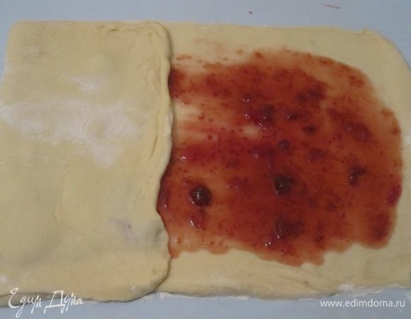 Готовое тесто раскатать в прямоугольник размером 60х30 см, смазать джемом, отступив на 1,5 см от края. Наверное, лучше взять густой джем или повидло. У меня какое-то количество джема при дальнейшей обработке просто вытекло на стол.