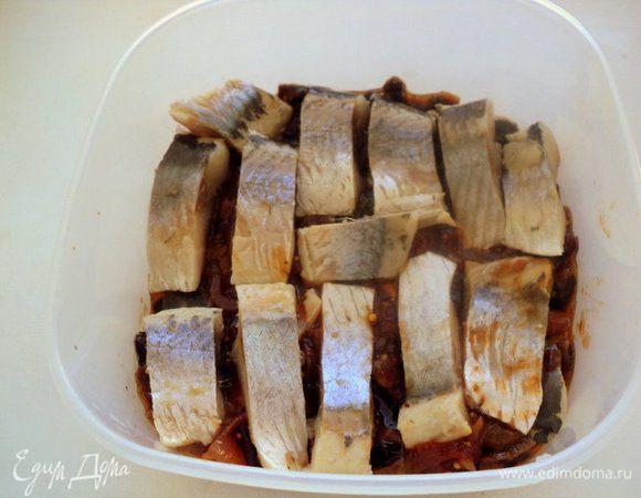 На дно судка выложить слой соуса, сверху кусочки сельди.