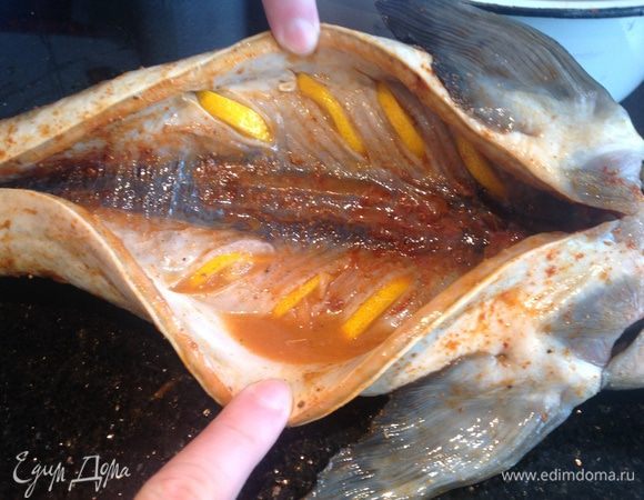 Рыбу натереть специями, сделать надрезы в брюшке и вставить туда лимон. Оставить пропитаться.