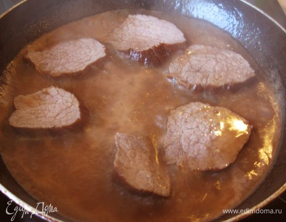 Выложил в сковороду ломтики мяса, убавил огонь и оставил говядину пропитываться медленно густеющим соусом.