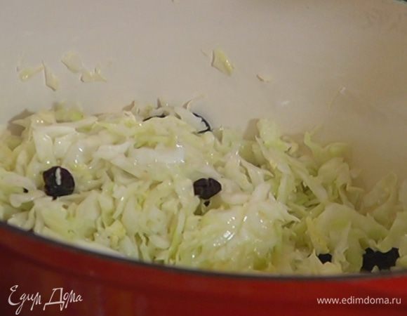 В тяжелой кастрюле разогреть оливковое и сливочное масло, выложить капусту и посолить ее. Добавить изюм и все перемешать.