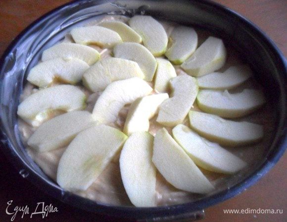 Форму диаметром 23 см смазать маслом. В подготовленную фору выложить тесто.
Яблоки вымыть, обсушить, удалить сердцевину, очистить и нарезать ломтиками. Выложить на тесто.