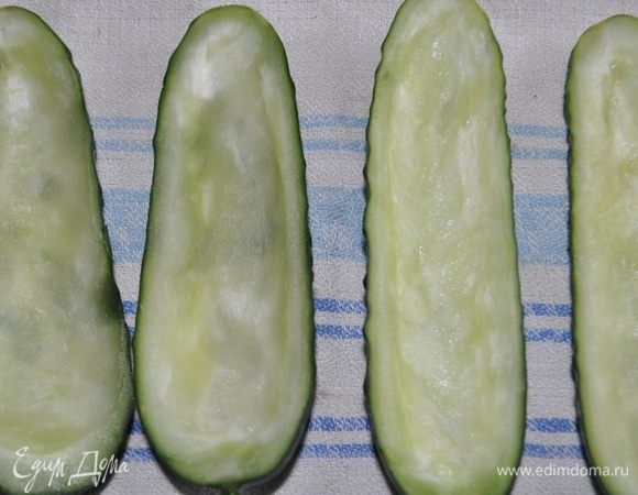 Разрезать огурцы вдоль, пополам.
Аккуратно удалить середину так, чтобы получились "лодочки".