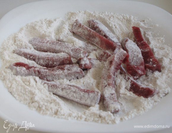 Приправить муку солью и перцем, обвалять в этой смеси мясо.