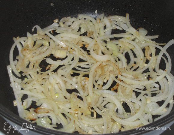 В сковороду положить оставшееся масло, нарезанный полукольцами лук и мелкорубленный чеснок. Обжаривать 5 минут.