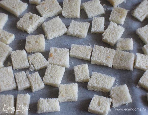 У хлеба обрезать корку и нарезать кубиками.Выложить на противень с пергаментом и подсушить в разогретой до 180 °С духовке до золотистого цвета.