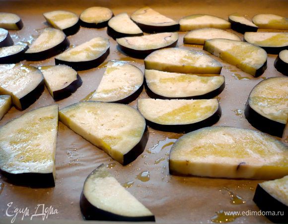 Духовку разогреем до 190 градусов. Баклажаны нарежем полукольцами, цукини — колечками. Выложим на застеленный пекарской бумагой противень, посолим и щедро сбрызнем оливковым маслом. Если баклажаны у вас с горечью, то стоит их присыпать солью и выложить на сито предварительно, дать постоять в течение минут двадцати, а потом промыть их, обсушить полотенцем и выложить на противень для запекания, как указано выше. Ставим в духовку запекаться до готовности и подрумянивания примерно минут на 15.