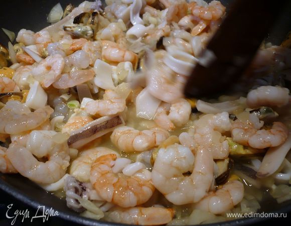 Грудку извлекаем из сковороды, перемешиваем с чесноком. Закладываем лук, жарим его буквально пару минут, выкладываем на него морепродукты и креветки, заливаем вином и тушим несколько минут. 