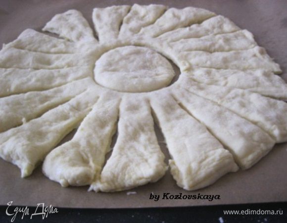 Когда тесто поднимется, разделить его на две или на три части, раскатать каждую часть так, чтобы получился круг. Для удобства  круг теста сразу перенести на противень. В центр ставим перевернутый бокал или стакан, чтобы получился вот такой кружок. Ножом делаем полоски.