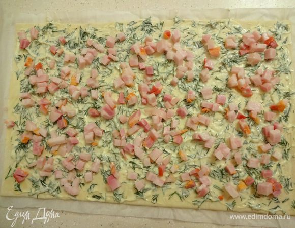 На размороженное тесто выложить уроп с майонезом, разровнять и равномерно выложить бекон.  