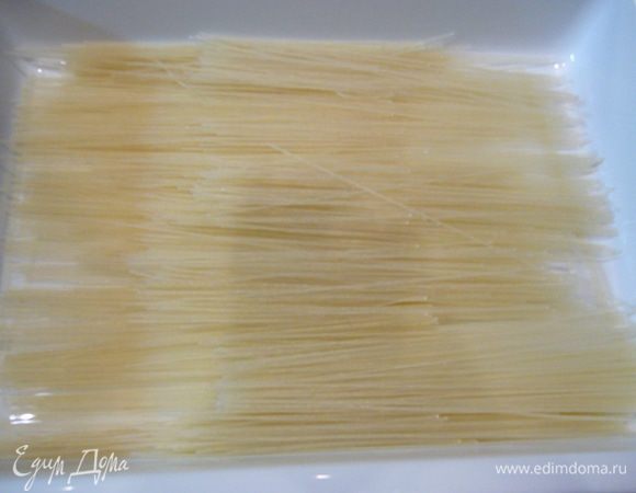 В емкость для запекания выложить рисовую лапшу, залить ее кипятком.