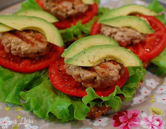 На каждую половинку булочки выложить лист салата, кружок помидора, котлетку и пару кусочков авокадо.