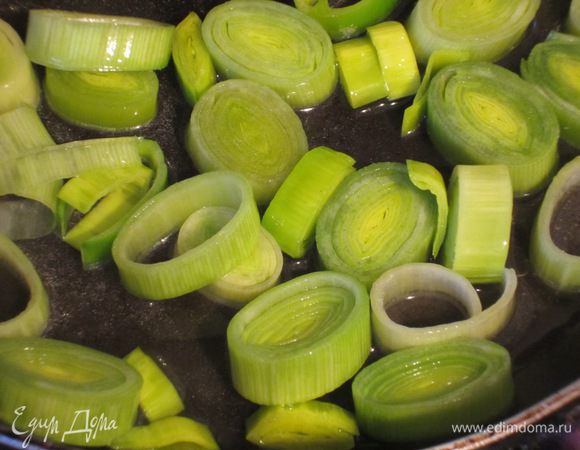 Лук-порей (светлую часть) нарезать колечками. Разогреть в сковороде оливковое масло и пассеровать лук на слабом огне 3-4 минуты.