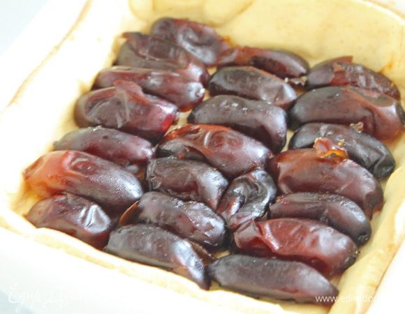 Финики разрезать пополам, удалить косточки и распределить ровным слоем на песочной основе.