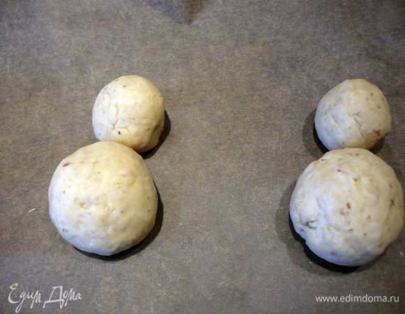 Духовку разогреваем до 200 градусов. Каждую из шести частей разделить на две части, при этом одна часть должна быть намного меньше другой. Скатать из всех двенадцати частей колобочки. На противень, выложенный пекарской бумагой, выложить маленький колобок и близко к нему - колобок побольше, так чтобы они едва касались друг друга.