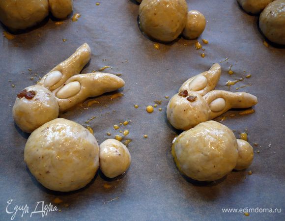 Смазываем зайчиков смесью молока и желтка (мы еще делали кругленькие хвостики). Изюм делим на две части — глазки. Делаем зайчикам глазки, половинки миндаля вдавливаем в ушки. Ставим в духовку на 20 минут. Достаем из духовки, даем остыть на решетке.