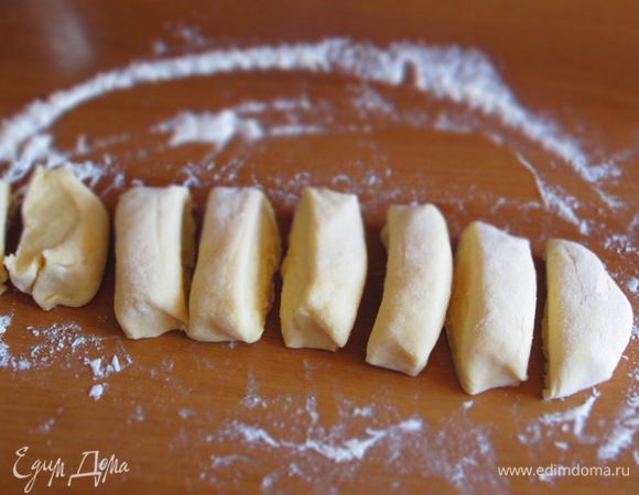 На присыпанной мукой рабочей поверхности сформировать колбаску и разделить её на 8 равных  частей.