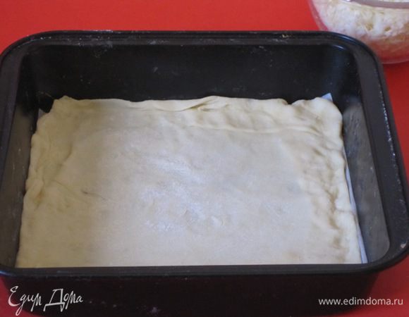 Взять прямоугольную или квадратную форму, у меня форма размером 20х20 см. Одну часть теста раскатать в тонкий пласт по размеру формы и выложить в смазанную маслом форму.
