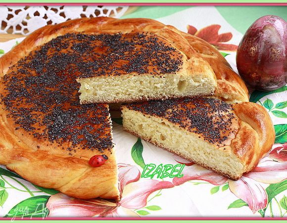 Большому куску придать форму круглой лепешки, из меньшего кусочка сделать 2 жгута, скрутить веревочкой и обложить лепешку вокруг. Смазать разболтанным желтком, обильно посыпать маком и выпекать в разогретой до 180С духовке до блестящей румяной корочки.