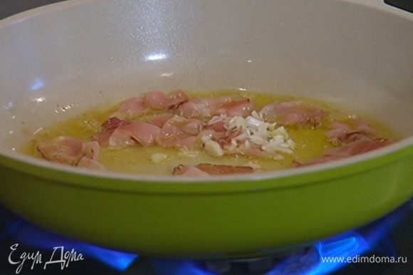 Разогреть в сковороде оливковое масло, добавить бекон, измельченный чеснок и обжарить бекон до золотистого цвета.