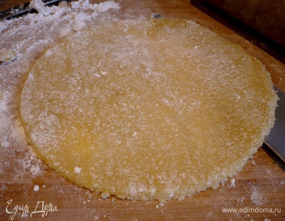 Сначала приготовим миндальную пасту. Для этого взобьем венчиком до пены яйцо, всыпем измельченные в блендере до состояния крошки лепестки миндаля (250 г) и сахар, добавим эссенцию горького миндаля, хорошо перемешаем руками до образования однородной марципановой массы. Делим тесто на четыре равные части. На присыпанную сахарной пудрой рабочую поверхность выкладываем первую часть, присыпаем слегка сверху сахарной пудрой и раскатываем в тонкую лепешку, вырезаем круг по диаметру формы (у меня 20 см). Аккуратно при помощи ножа с длинным и широким лезвием преподнимаем пласт и перекладываем его на пленку, сверху также прикрываем пленкой (если пласт разломается на две части, это не страшно, после перекладывания его можно будет склеить). То же самое проделываем с остальными двумя частями марципана. Можно раскатывать марципан сразу на пленке.