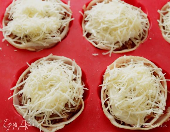 Сверху разложить оставшийся фарш так, чтобы яйца оказались внутри и были полностью покрыты фаршем. Сверху немного смазать майонезом или сметаной и посыпать тертым сыром.