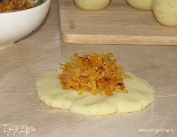 Каждый колобок расплющить и положить внутрь начинку. Собрать края теста к центру и слепить аккуратный круглый пирожок.