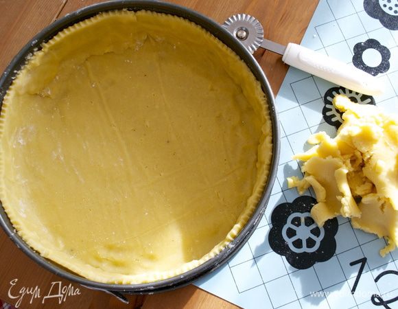 Перенести и выложить тесто в форму для выпечки. Излишки теста обрезать и подровнять край основания пирога.