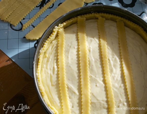 Из оставшегося теста раскатать пласт и нарезать полоски с помощью рельефного ножа... Аккуратно выложить поверх крема полоски нарезанного теста в одном направлении...