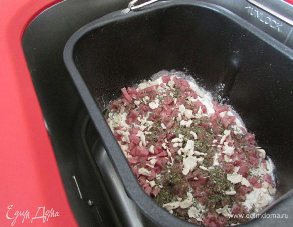 Поместите ингредиенты в хлебопечь в следующей последовательности: вода, масло оливковое, соль, сахар, мука, молоко сухое, ветчина, дрожжи. Базилик положите в диспенсер или засыпьте потом, по сигналу в контейнер. Включите хлебопечку (программа “Французский хлеб”), для размера 750 г, корочка средняя).