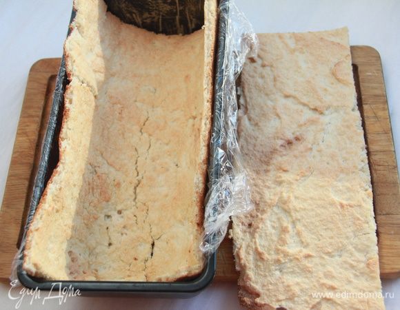 Сразу же разрезать бисквит на 2 части: 1/3 и 2/3 прямоугольника (большая часть будет стенками и должна по размеру подходить к форме, в которой будет собираться торт; меньшая часть - прямоугольник 26х12см.
Бисквит быстро твердеет, поэтому необходимо быстро поместить 2/3 части в форму, застеленную пищевой пленкой. Оставшаяся часть будет дном торта.