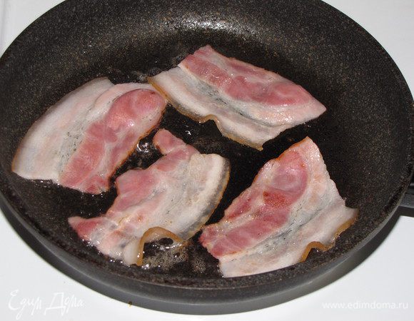 Полоски бекона разрезать на 3 части и обжарить на сковороде с двух сторон.